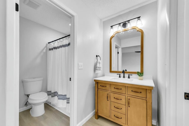 bathroom with a textured ceiling, vanity, baseboards, and wood finished floors