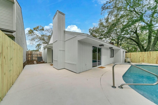 rear view of house featuring a patio, central AC unit, and a chimney