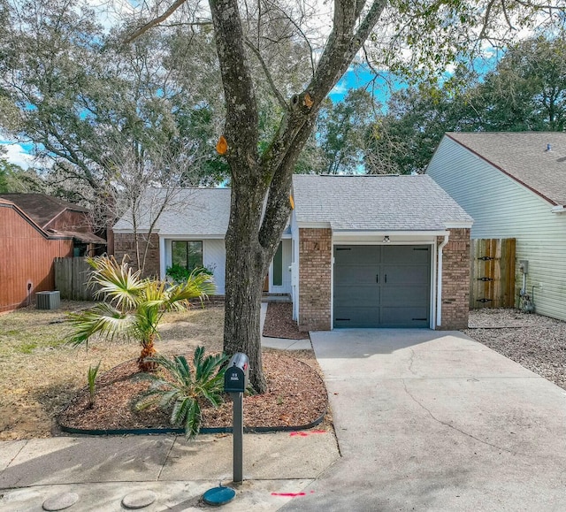 view of front of house featuring a garage, brick siding, driveway, and fence