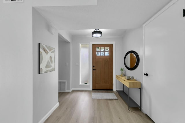 entrance foyer featuring visible vents, baseboards, and light wood finished floors