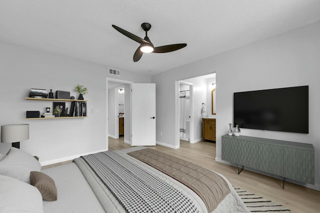 bedroom with a ceiling fan, wood finished floors, visible vents, baseboards, and ensuite bath