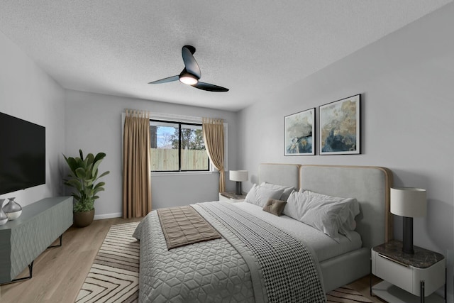 bedroom with baseboards, light wood-style flooring, a textured ceiling, and ceiling fan