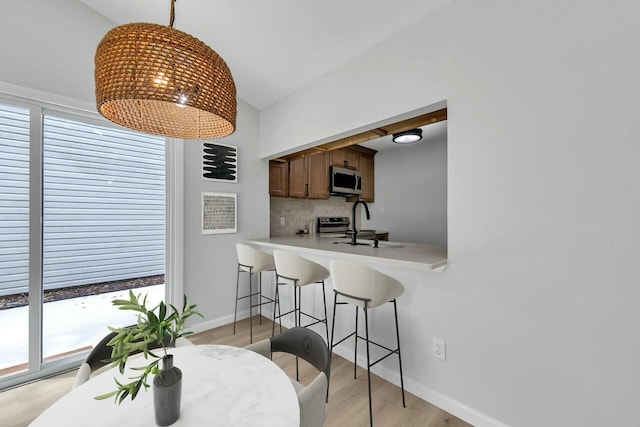 dining space featuring baseboards, light wood-style floors, and vaulted ceiling