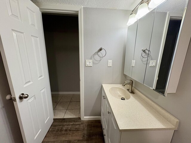 bathroom with a textured ceiling, tile patterned floors, vanity, and baseboards