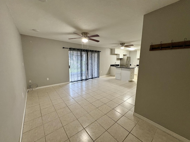 unfurnished living room featuring baseboards, a textured ceiling, and light tile patterned flooring