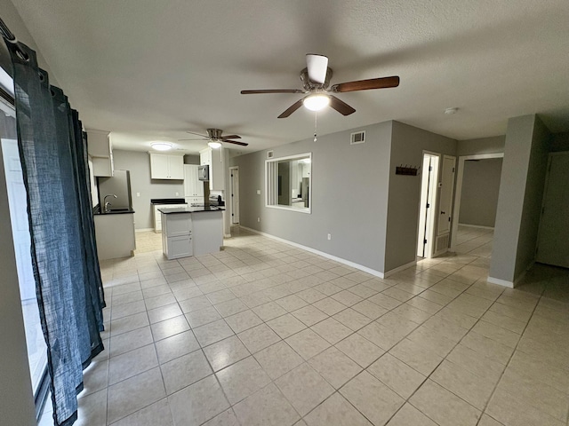 interior space featuring open floor plan, light tile patterned flooring, dark countertops, and visible vents