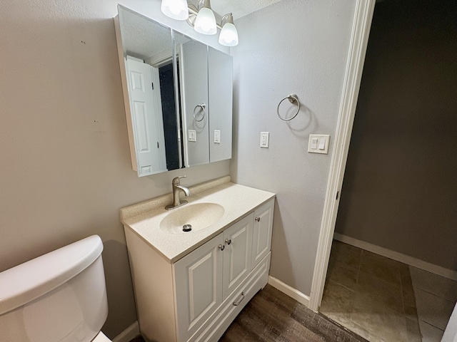 bathroom with toilet, baseboards, and vanity