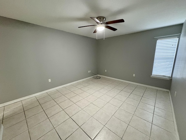 spare room with a ceiling fan and baseboards