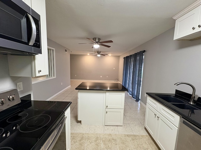 kitchen featuring dark countertops, a ceiling fan, appliances with stainless steel finishes, and a sink