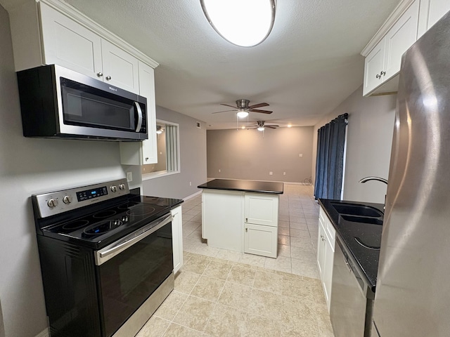 kitchen featuring appliances with stainless steel finishes, dark countertops, white cabinetry, and a sink