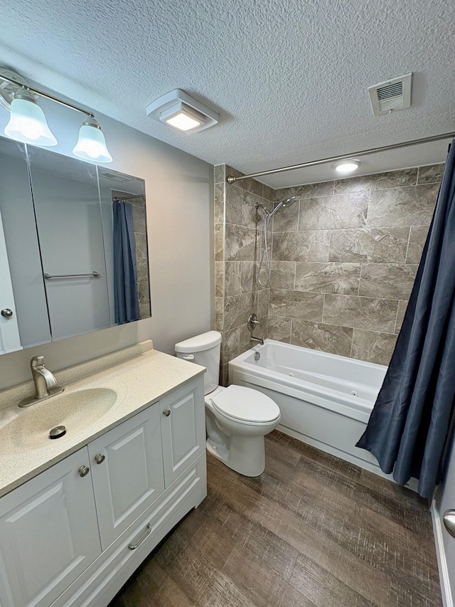 full bathroom featuring shower / tub combo, visible vents, wood finished floors, a textured ceiling, and vanity