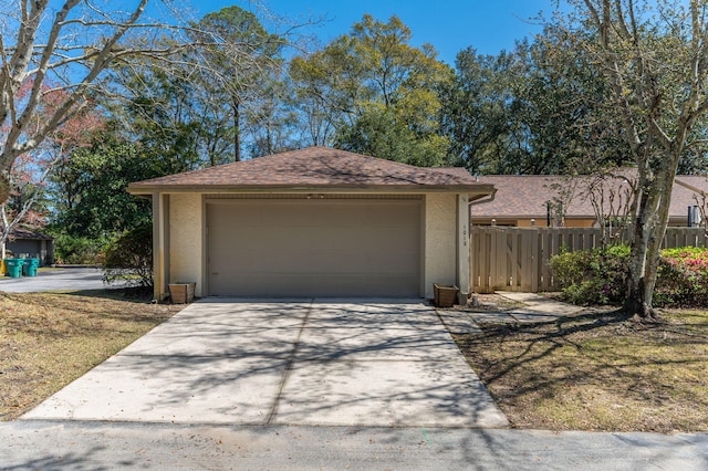 garage with concrete driveway and fence