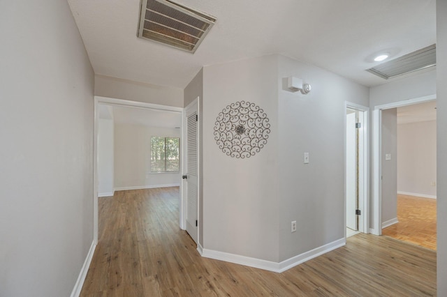 corridor with visible vents, baseboards, and wood finished floors