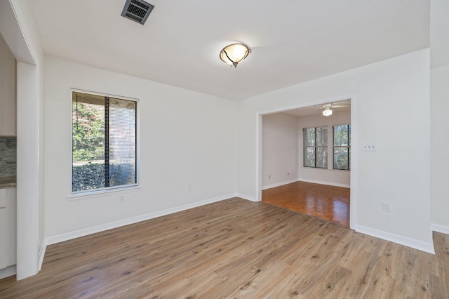 empty room featuring visible vents, baseboards, light wood-style floors, and ceiling fan