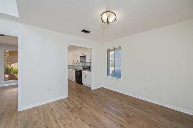 unfurnished living room featuring a skylight, visible vents, baseboards, and wood finished floors