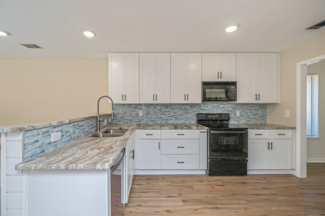 kitchen featuring tasteful backsplash, white cabinets, black appliances, and a sink