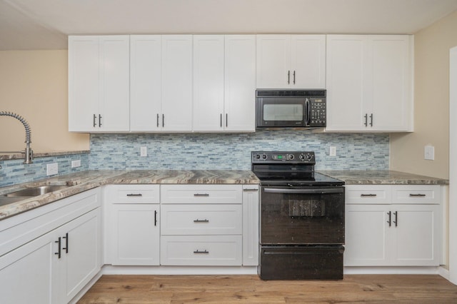 kitchen featuring a sink, light stone countertops, black appliances, and white cabinetry