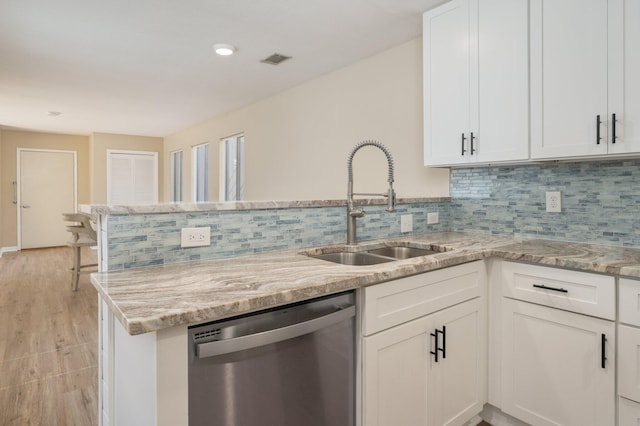 kitchen with visible vents, a sink, light stone counters, white cabinets, and dishwasher