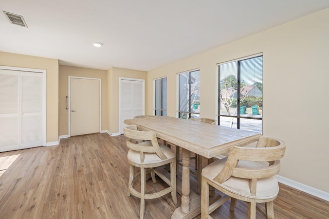 dining space featuring light wood-style floors, baseboards, and visible vents