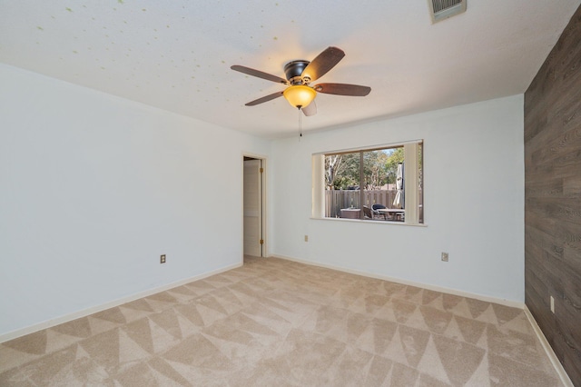 empty room featuring visible vents, baseboards, light colored carpet, and a ceiling fan