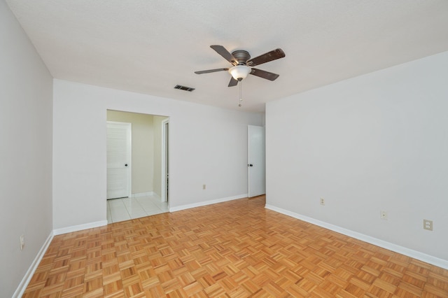 empty room with a ceiling fan, visible vents, and baseboards