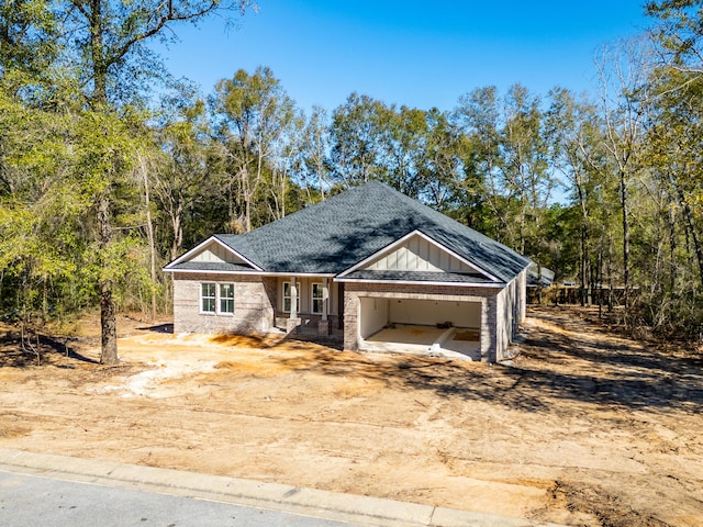 view of front facade with board and batten siding, brick siding, driveway, and a shingled roof