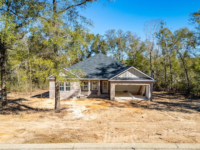 view of front of house featuring driveway, a shingled roof, board and batten siding, and brick siding