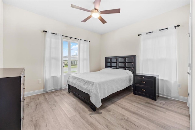 bedroom featuring a ceiling fan, light wood-style floors, and baseboards