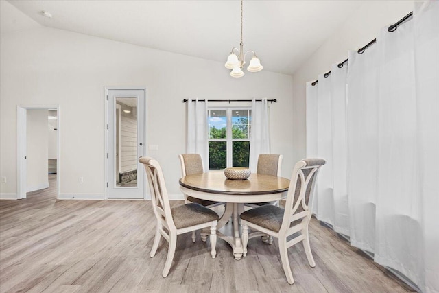 dining area featuring a notable chandelier, light wood-type flooring, baseboards, and vaulted ceiling