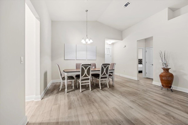 dining room featuring vaulted ceiling, light wood-style floors, visible vents, and baseboards