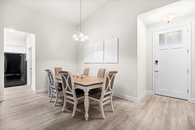 dining space featuring baseboards, light wood-style floors, and vaulted ceiling