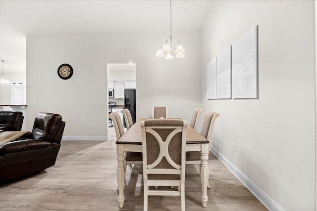 dining room featuring a notable chandelier, baseboards, and light wood finished floors