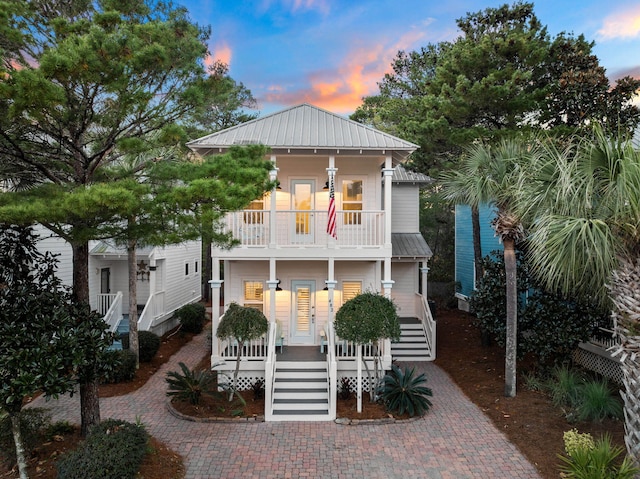 view of front of house with covered porch, metal roof, a balcony, and stairs