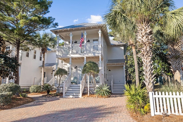 view of front of house featuring metal roof, fence, a balcony, and a standing seam roof