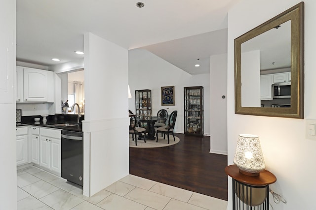 kitchen featuring dishwashing machine, dark countertops, a sink, white cabinetry, and stainless steel microwave