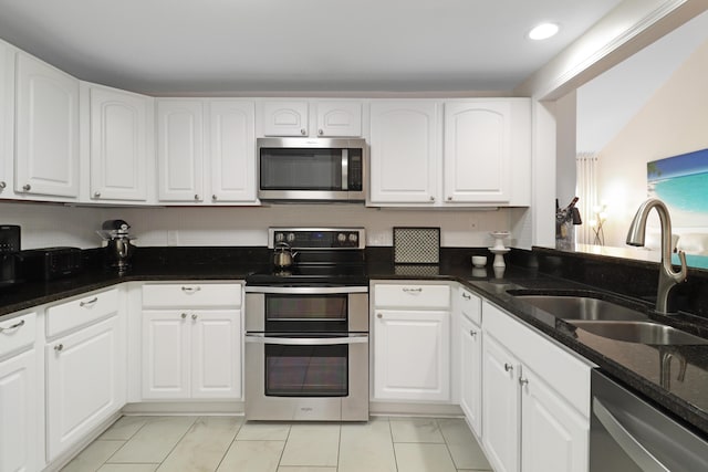 kitchen featuring dark stone countertops, recessed lighting, white cabinets, stainless steel appliances, and a sink