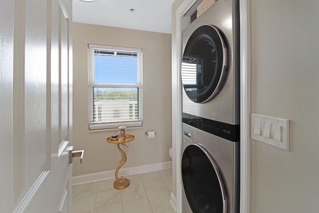 laundry area featuring baseboards, stacked washer and dryer, and laundry area