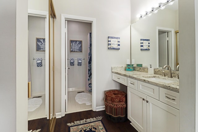 bathroom featuring baseboards, wood finished floors, and vanity