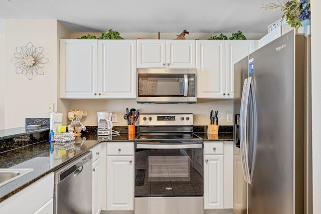 kitchen featuring appliances with stainless steel finishes, dark stone counters, and white cabinetry