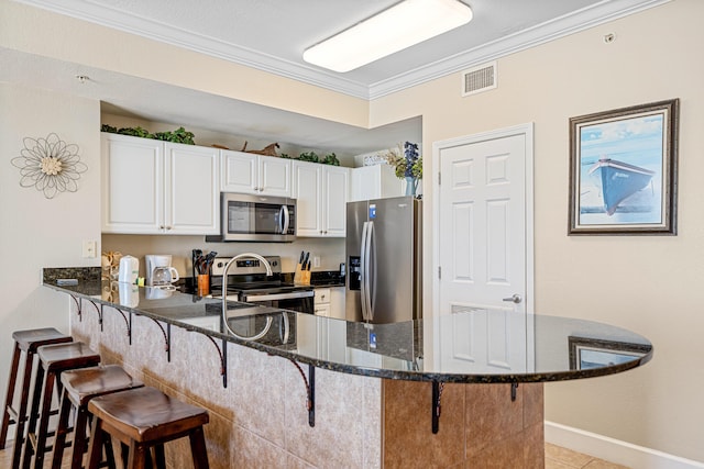 kitchen featuring a peninsula, a breakfast bar, visible vents, appliances with stainless steel finishes, and crown molding