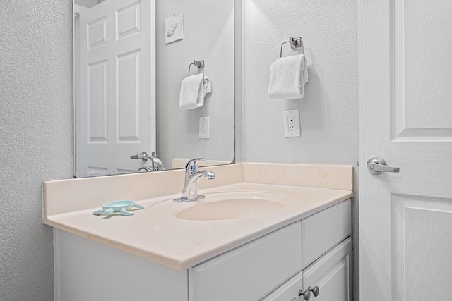 bathroom featuring a textured wall and vanity