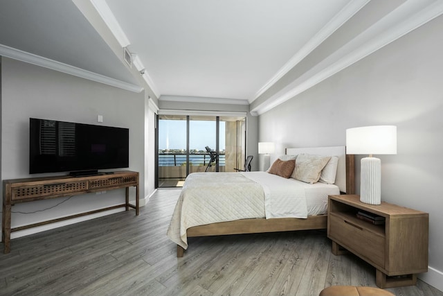 bedroom with baseboards, wood finished floors, crown molding, and access to exterior