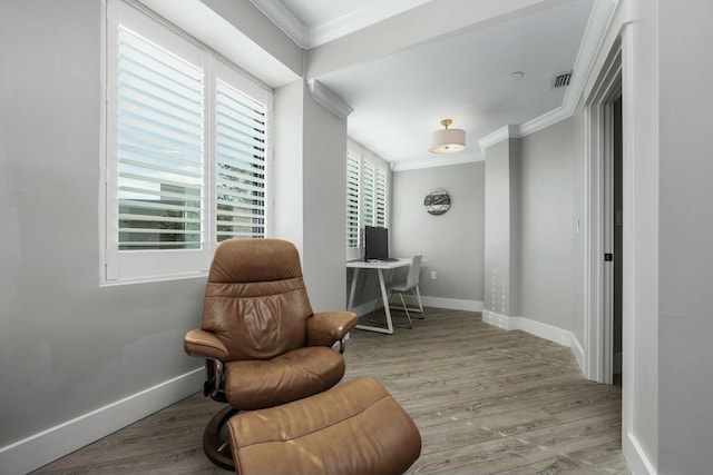 living area with baseboards, wood finished floors, visible vents, and ornamental molding