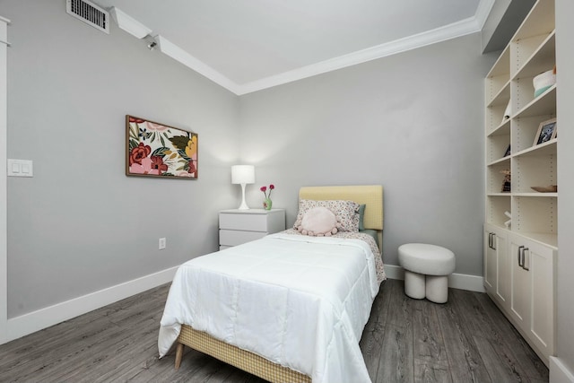 bedroom featuring visible vents, baseboards, wood finished floors, and crown molding