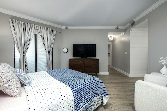 bedroom with crown molding, wood finished floors, visible vents, and baseboards