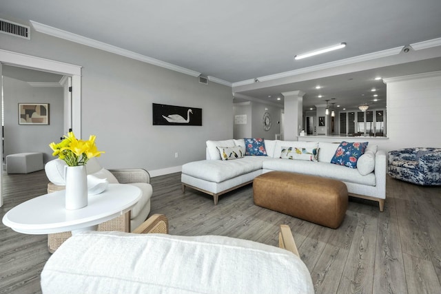 living area featuring crown molding, wood finished floors, visible vents, and baseboards