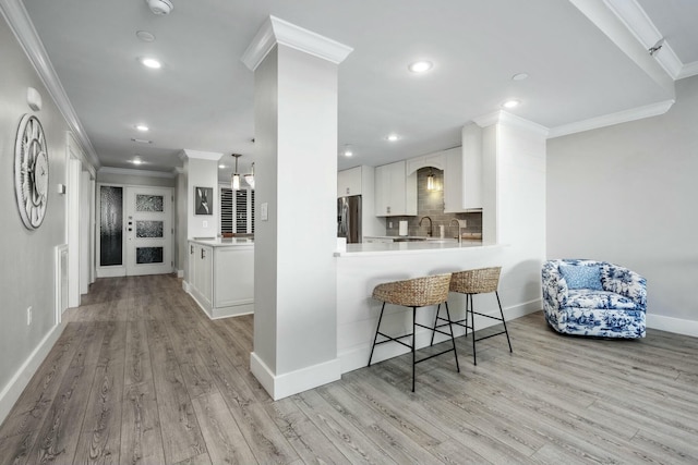 kitchen featuring tasteful backsplash, a breakfast bar, crown molding, and stainless steel refrigerator with ice dispenser