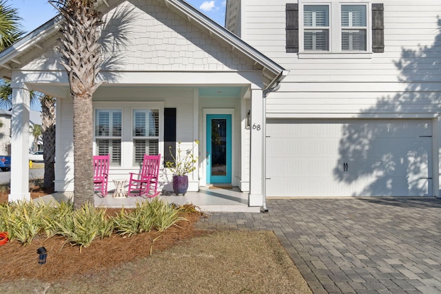 doorway to property with decorative driveway, covered porch, and an attached garage