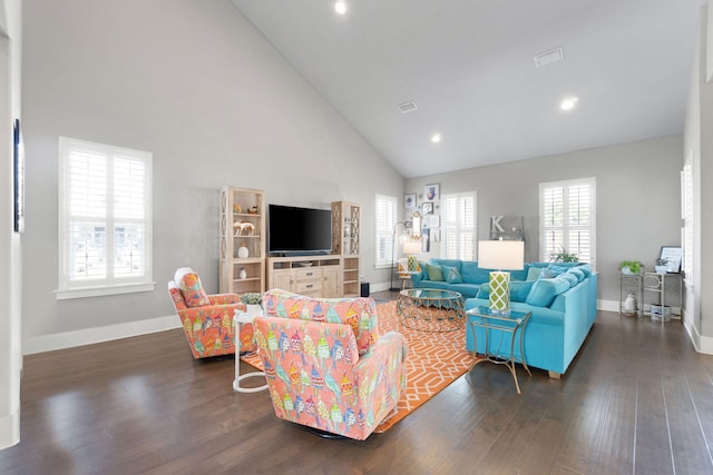 living area featuring dark wood-type flooring, a healthy amount of sunlight, high vaulted ceiling, and baseboards