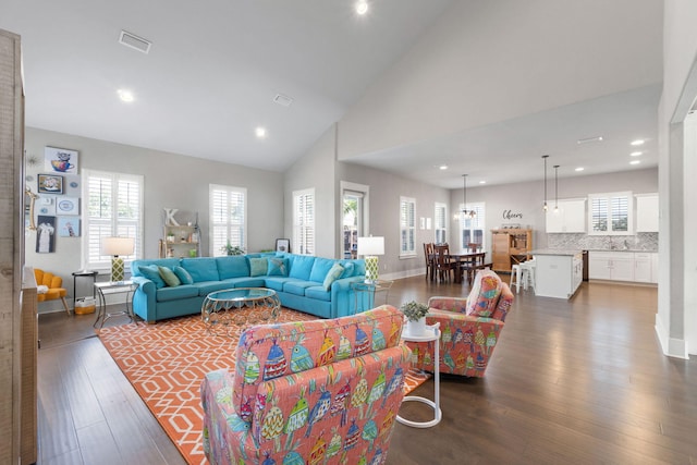 living area featuring dark wood-type flooring, recessed lighting, visible vents, and high vaulted ceiling